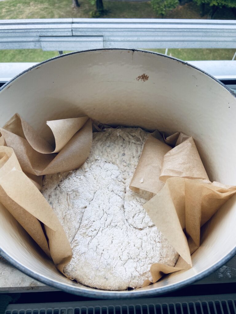 Scored dough on parchment paper inside dutch oven prior to baking